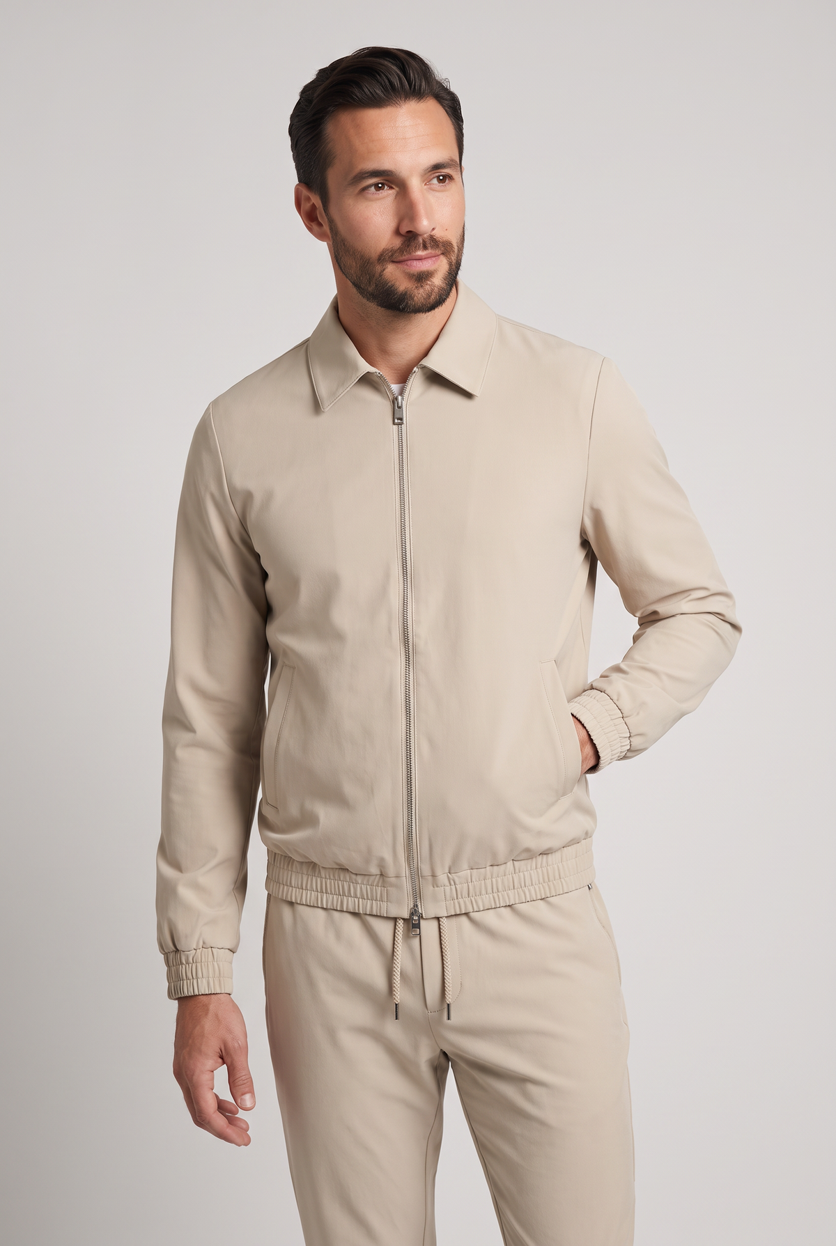Astos tech suit beige - model studio vooraanzicht, jack dicht