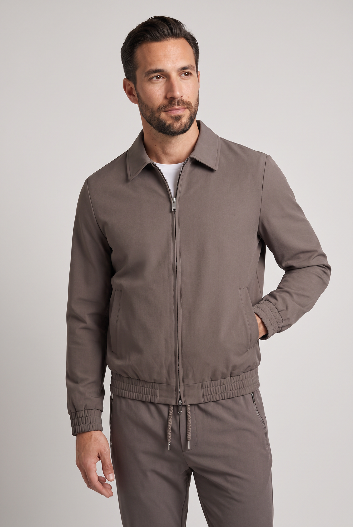 Astos tech suit bruin (taupe) - model studio vooraanzicht, jack dicht