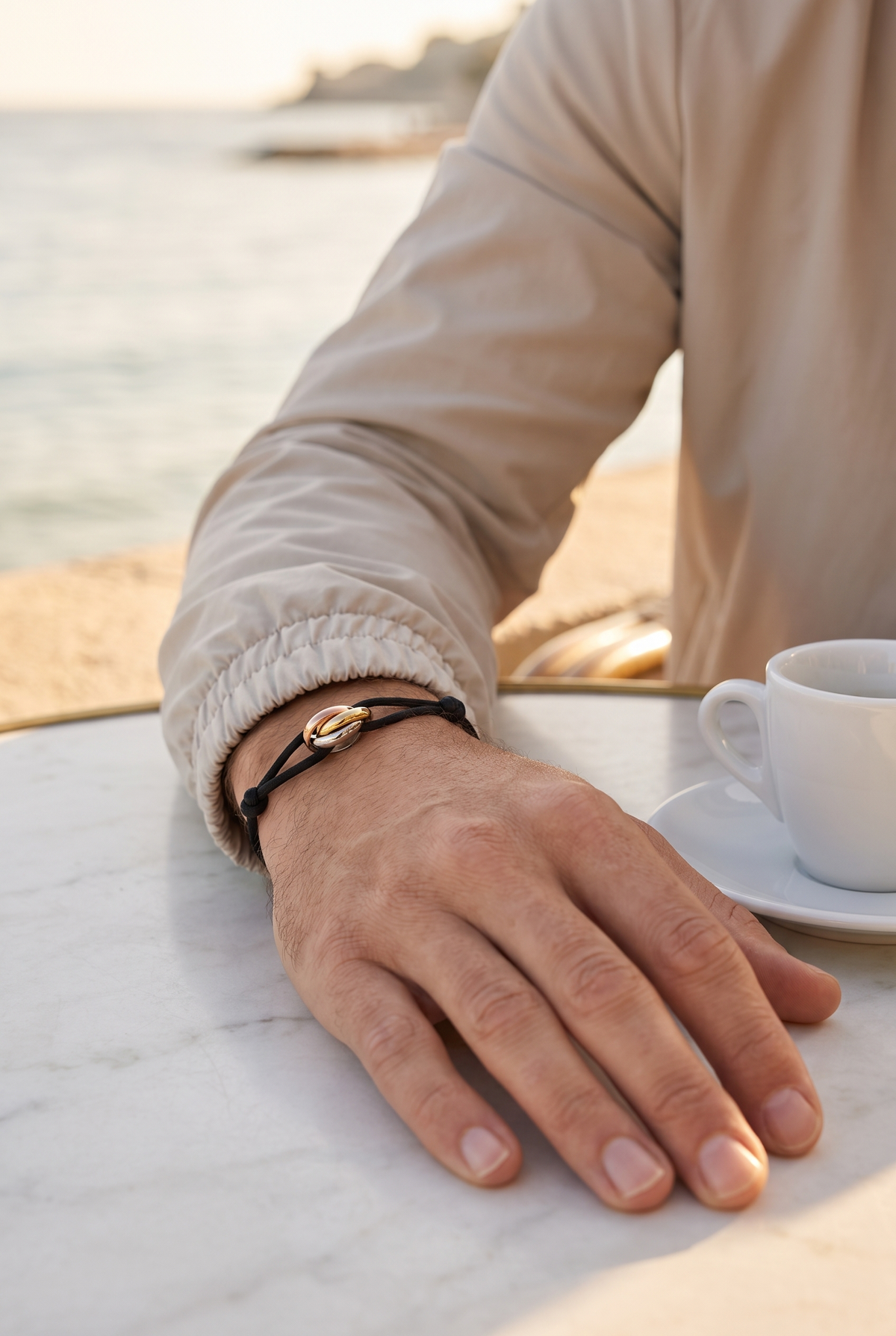 Astos rope armband zwart koord met drie ringen - lifestyle op een terras