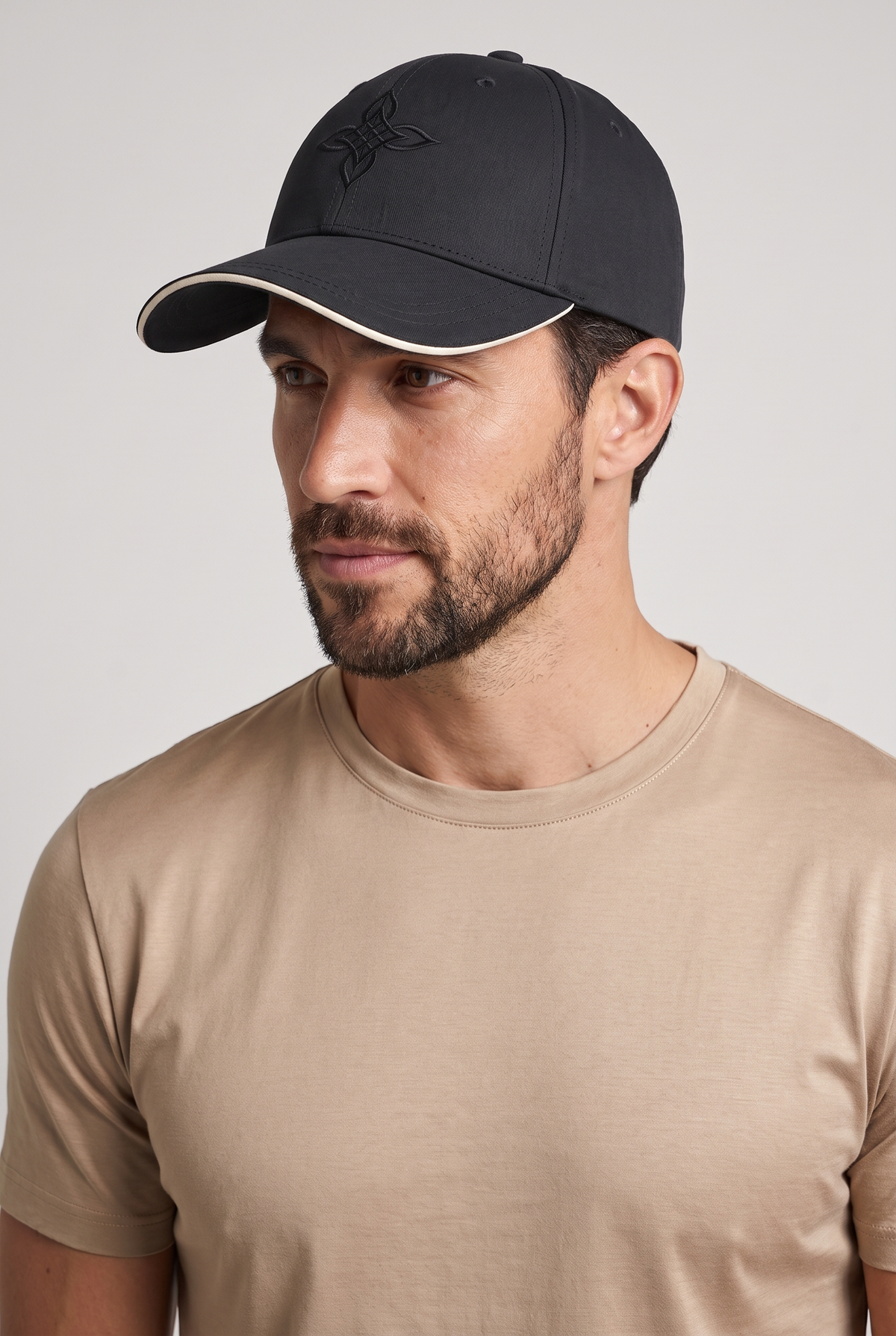 Baseball cap zwart, gedragen door model, vooraanzicht met geborduurd embleem